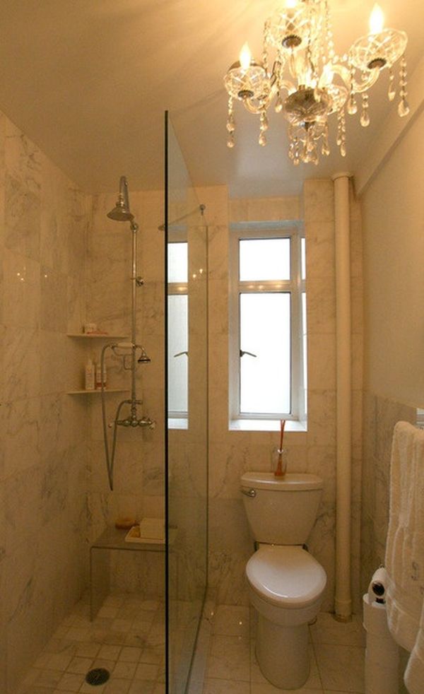 Banheiro pequeno com lustre e divisória de vidro